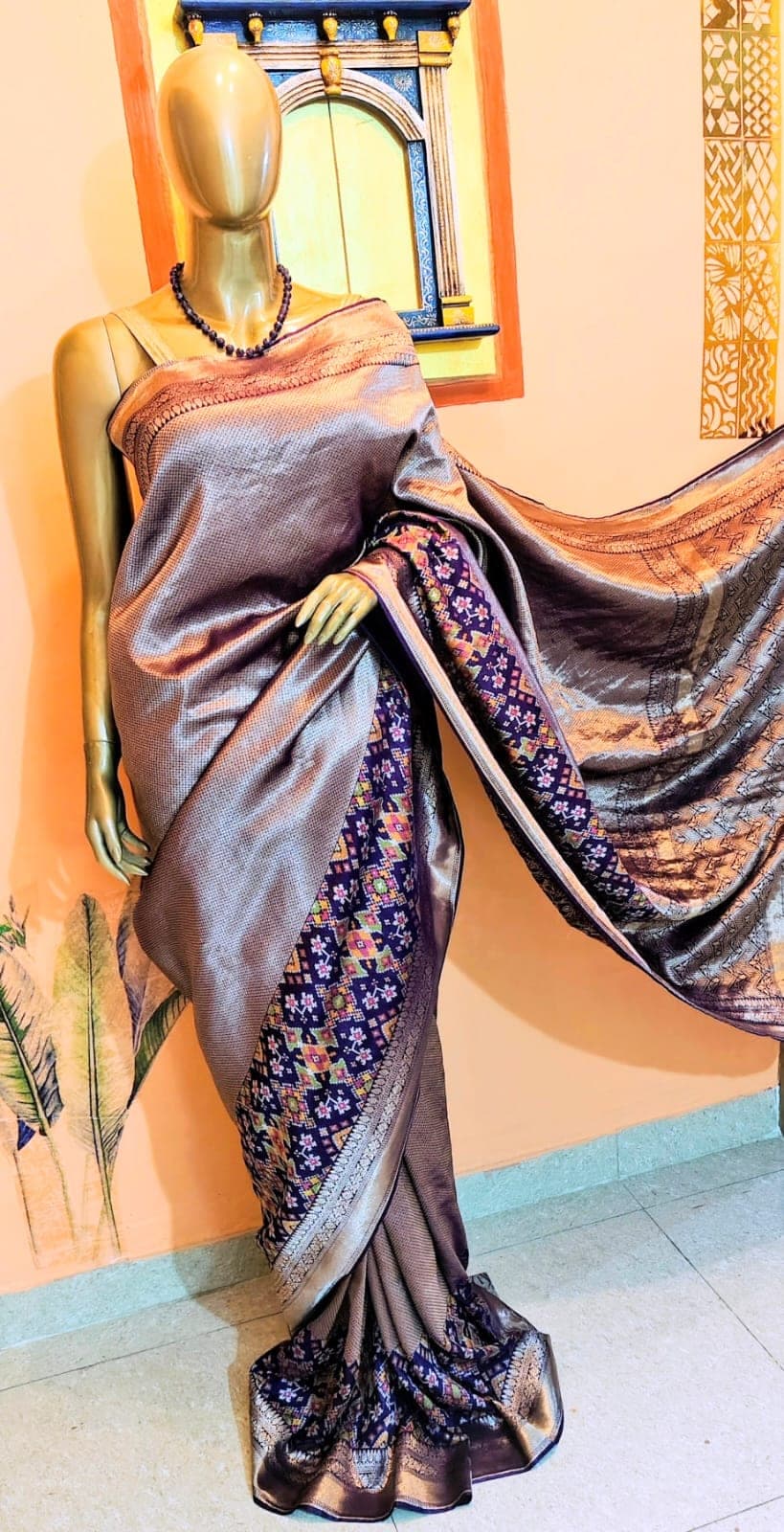 Antique-gold saree with a violet contrast border, on a stand