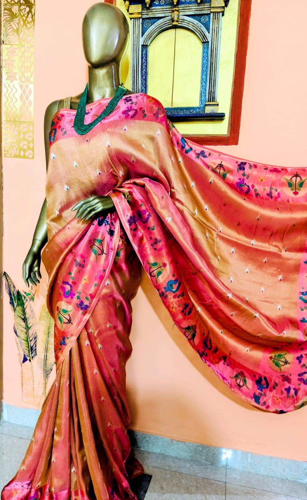 Coral saree with a pink figured pallu, draped on a stand