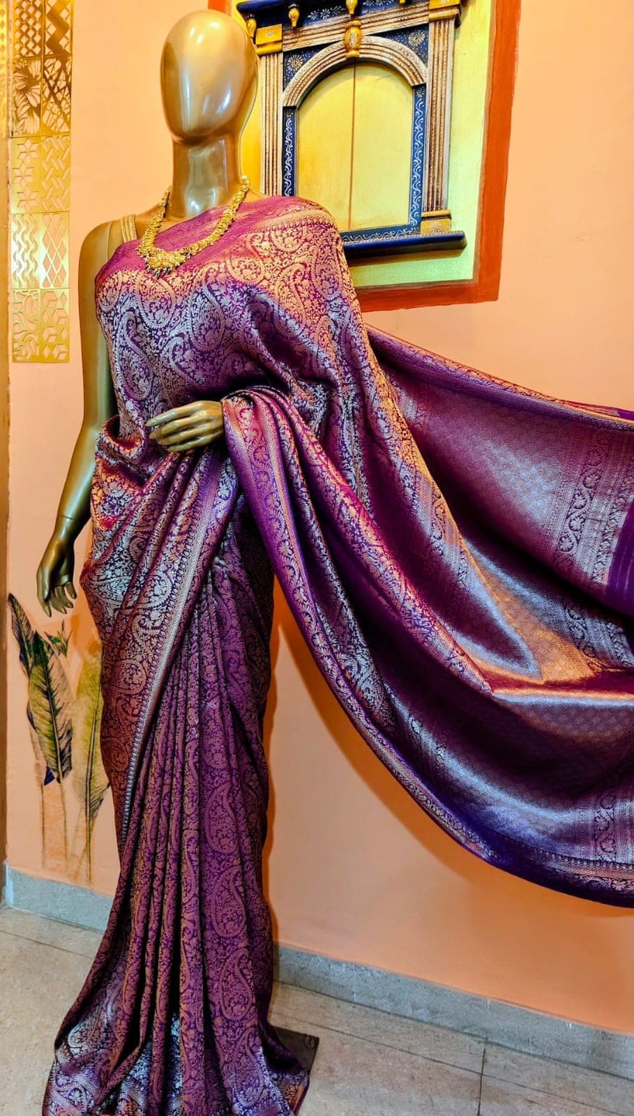 Purple saree with a gold paisley pattern, draped on a stand