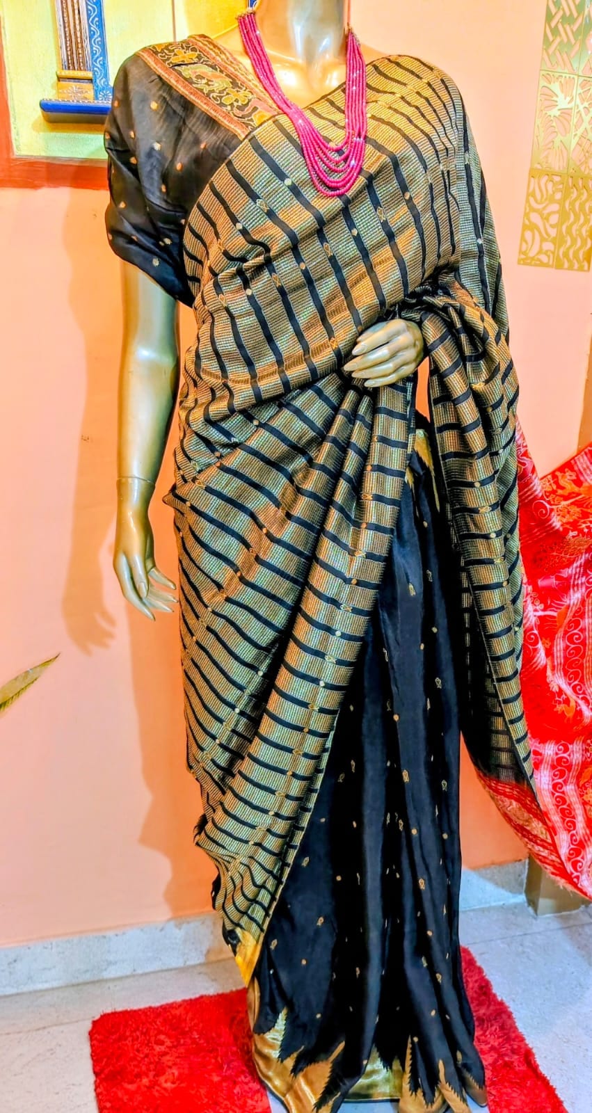Black saree with an all-over gold geometric stripe weave, draped on a stand