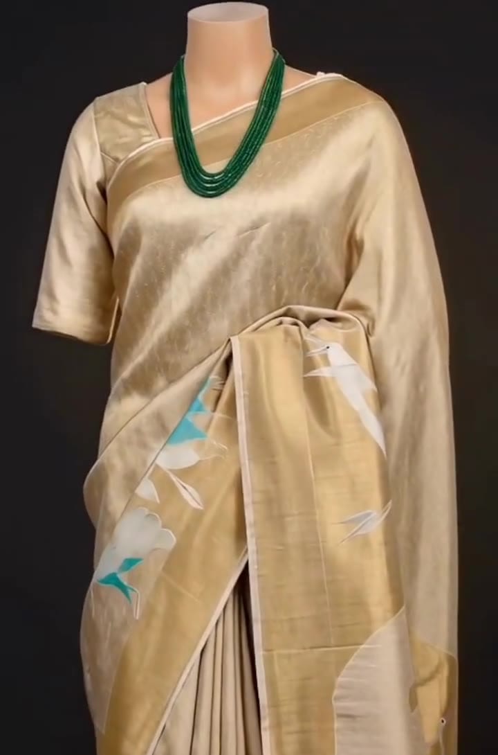 Champagne-gold tissue saree with crane motifs, draped on a stand