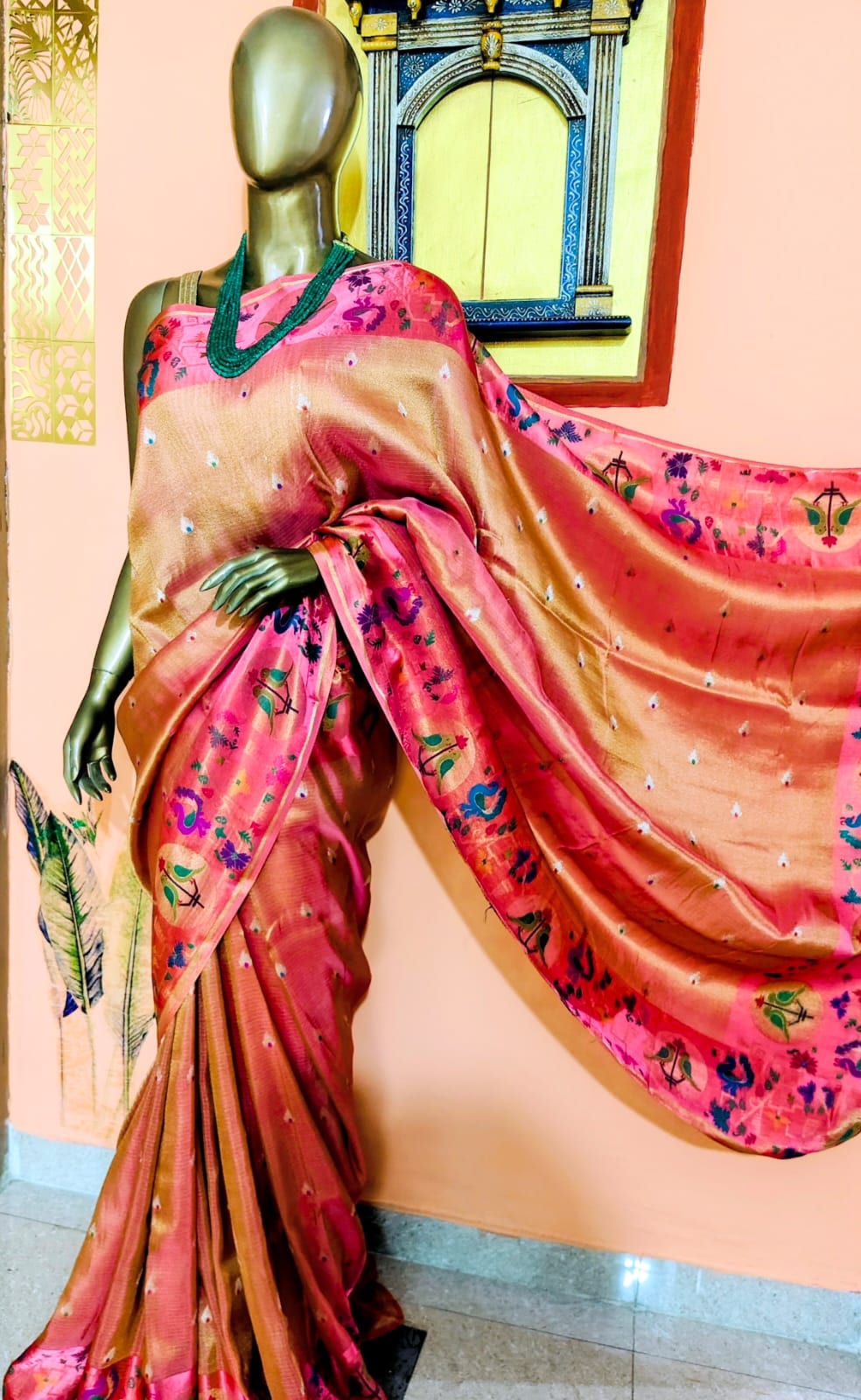 Coral saree with a pink figured pallu, draped on a stand