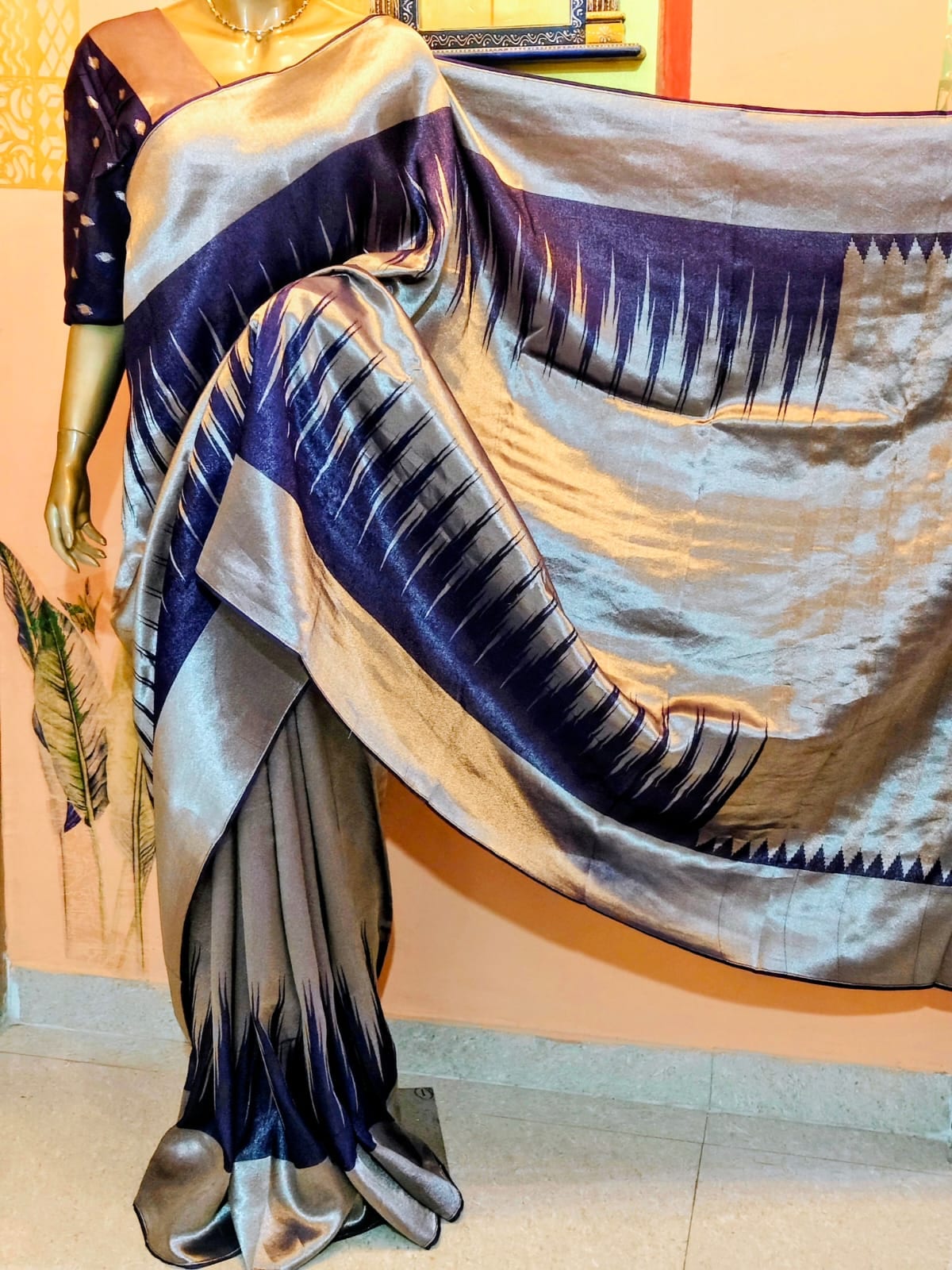 Navy blue and silver-grey saree with a woven temple border, draped on a stand